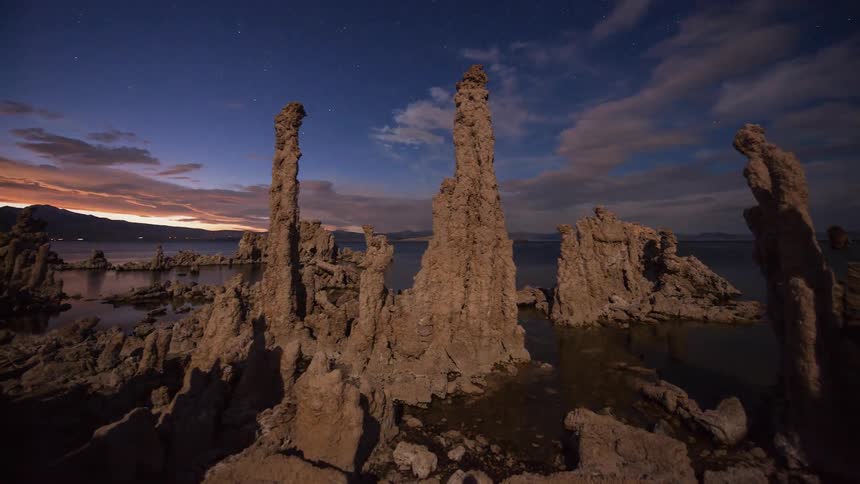 Clouds pass over ocean rock formations at sunset