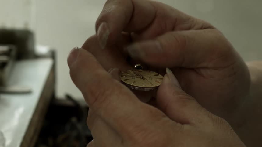 A watchmaker winds a clock piece