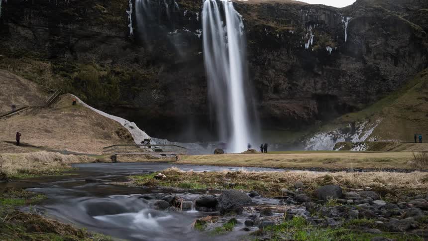 People hike near a waterfall