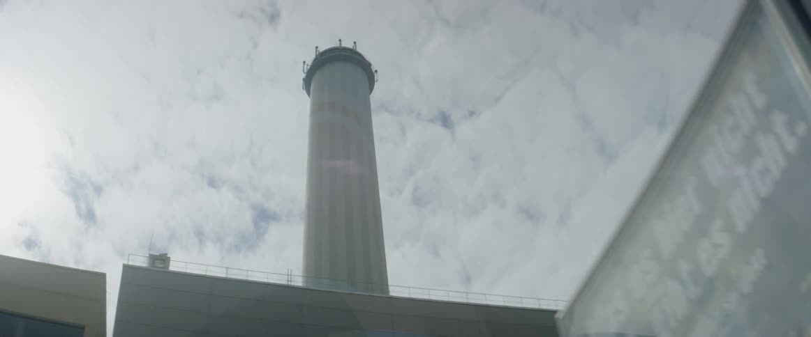 Smokestack on a factory with sun behind it