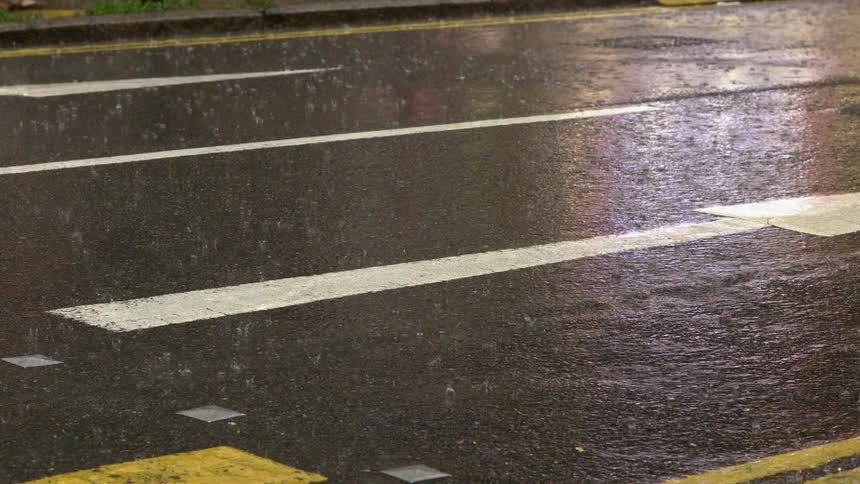 Rain falls on a paved street