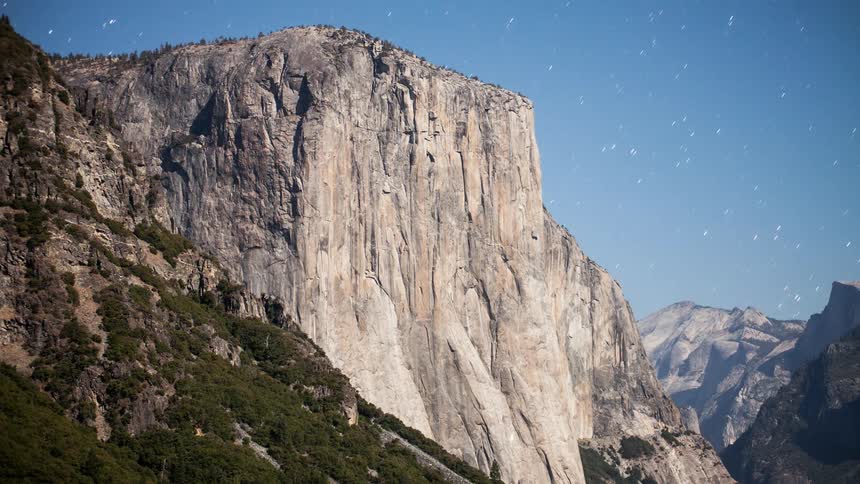 Stars move across the sky over cliffs and ridges