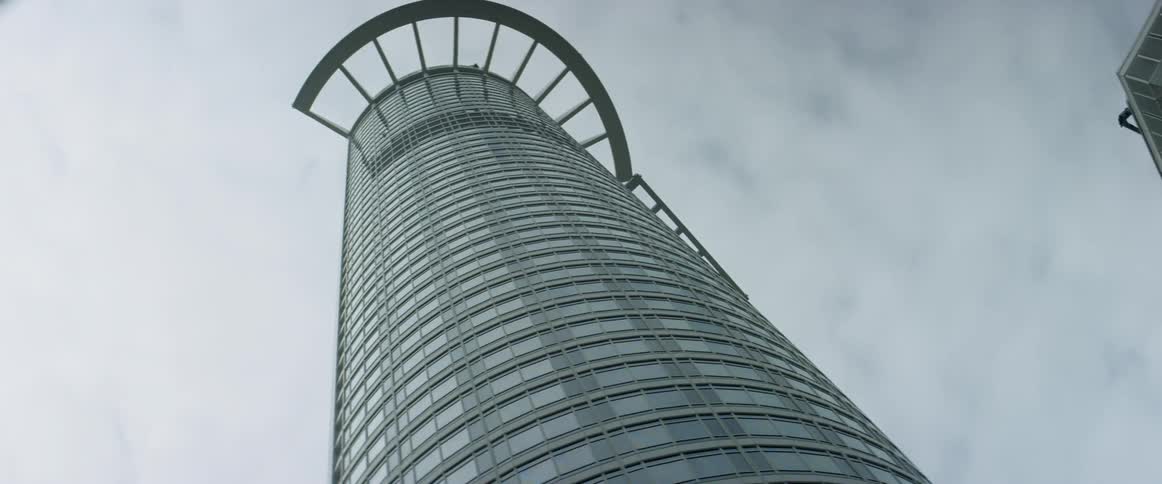 Clouds are hanging above the top of a skyscraper in a city during the day