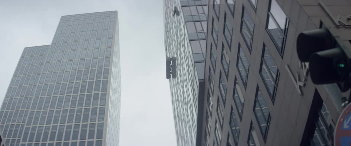 A window washing rig is hanging from a skyscraper on a cloudy day