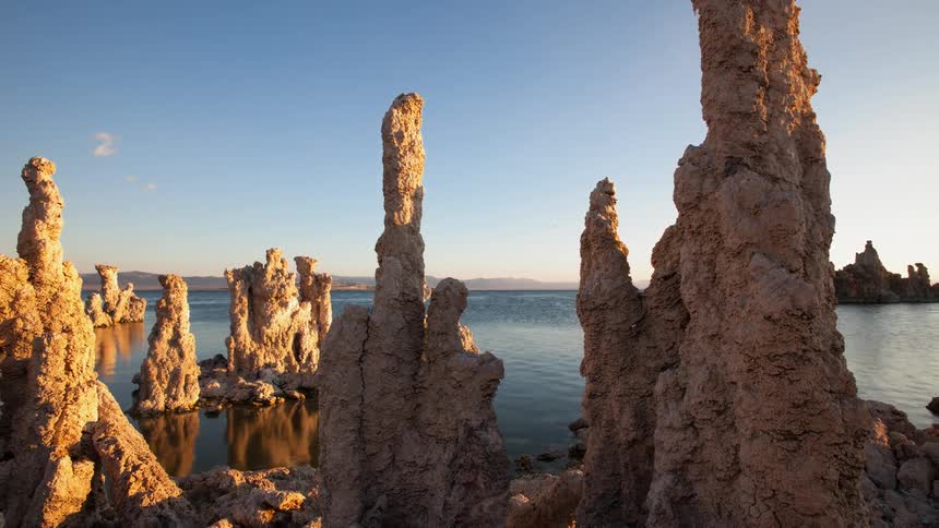 Rock formations sit in a lake at sunrise