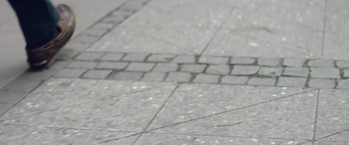 Two men are walking on a city sidewalk during the day