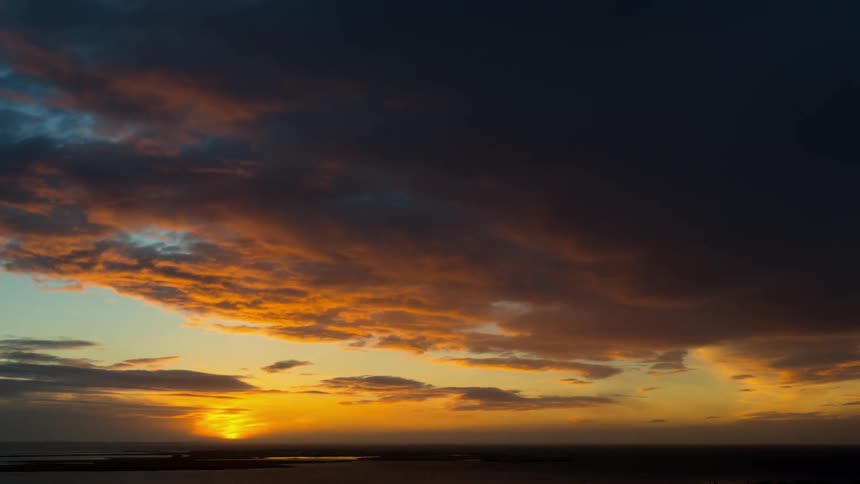 Clouds are drifting in the sky as the sun is setting