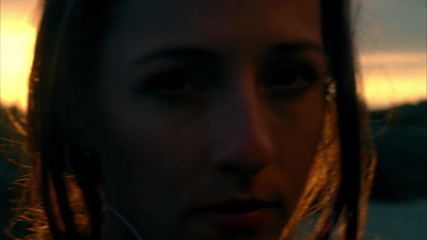 A woman is standing and staring outside at sunset