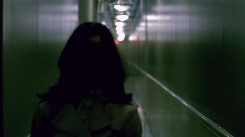 A woman is walking through a hallway at night