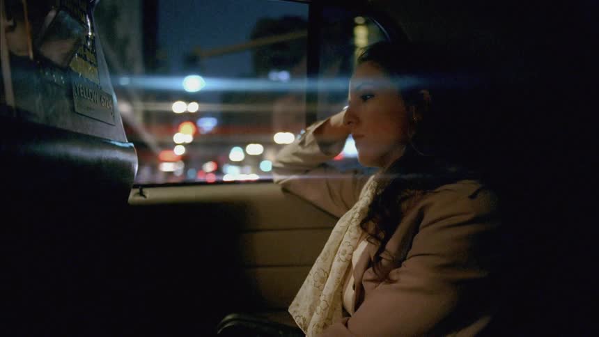 A woman is riding in a taxi looking tired