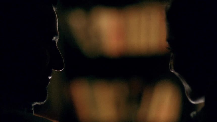A man and woman smile and kiss in the dark