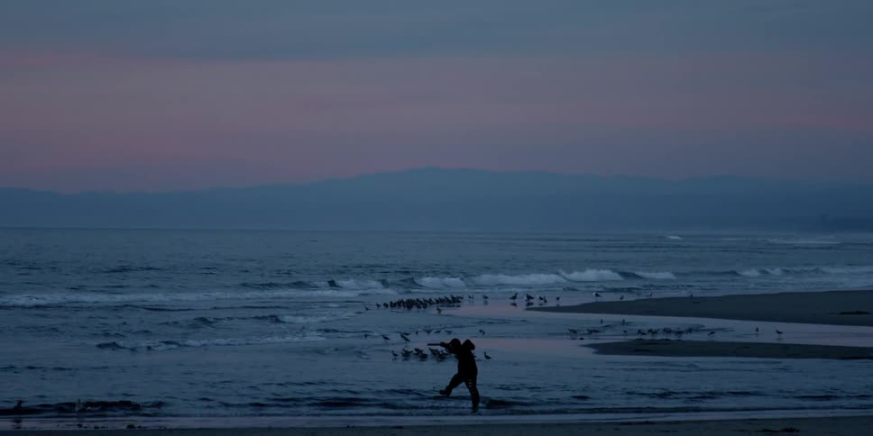 A person runs and jumps on a beach at sunset