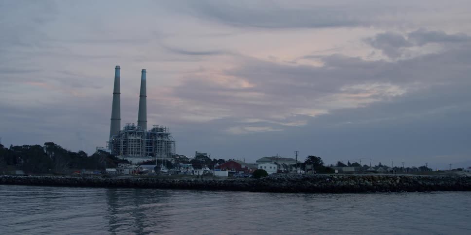 A river flows by a factory at sunset