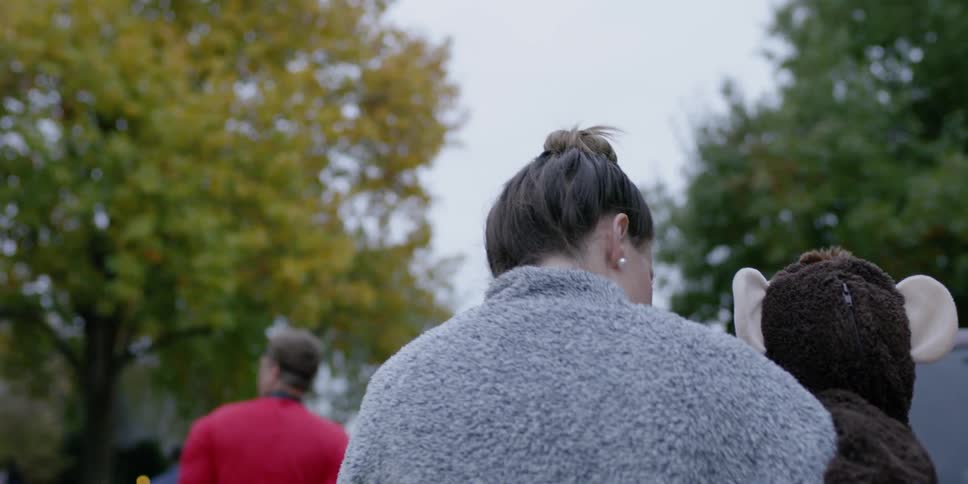 Group of people walk outside near trees on a cloudy day