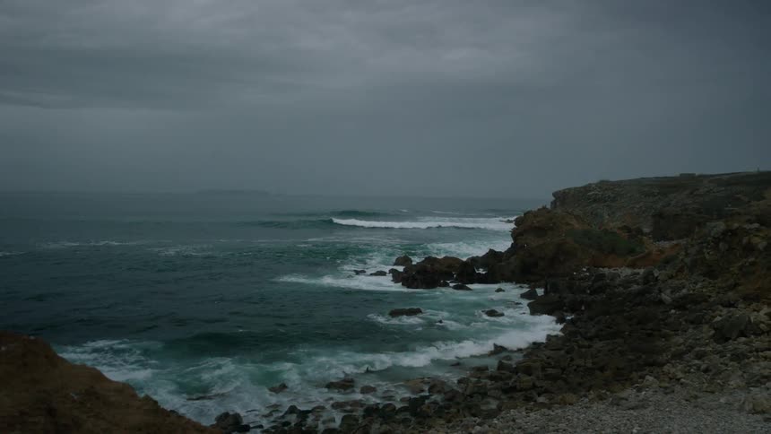 Waves are crashing against the rocks on a beach on a stormy evening