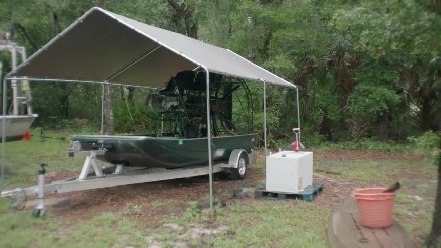 A boat is parked beneath a tarp