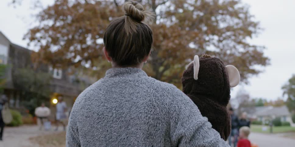 A mom carries her costumed toddler on halloween