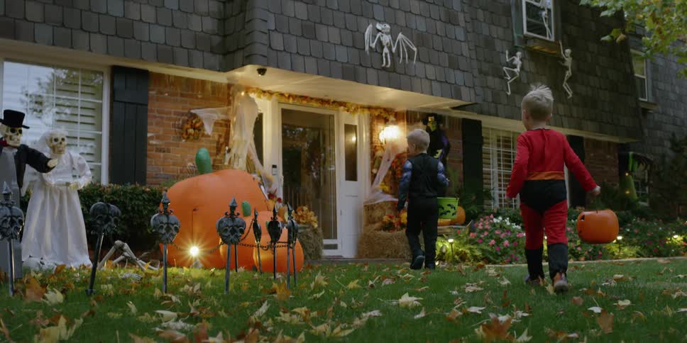Children are running toward a house on halloween at dusk