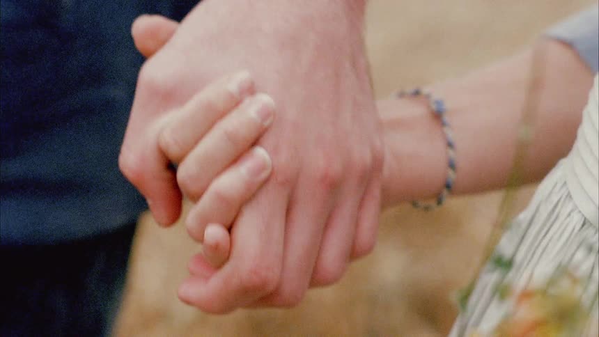 A father and daughter hold hands while walking outside