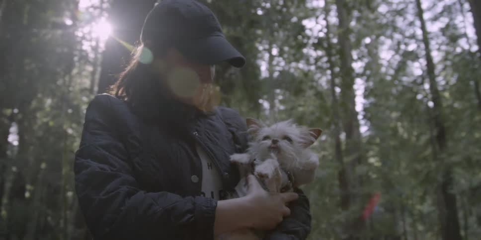 A woman holds a dog in a forest