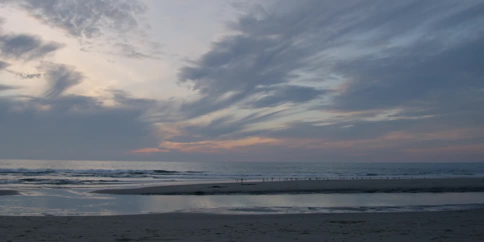 Clouds are hanging offshore at a beach at dusk