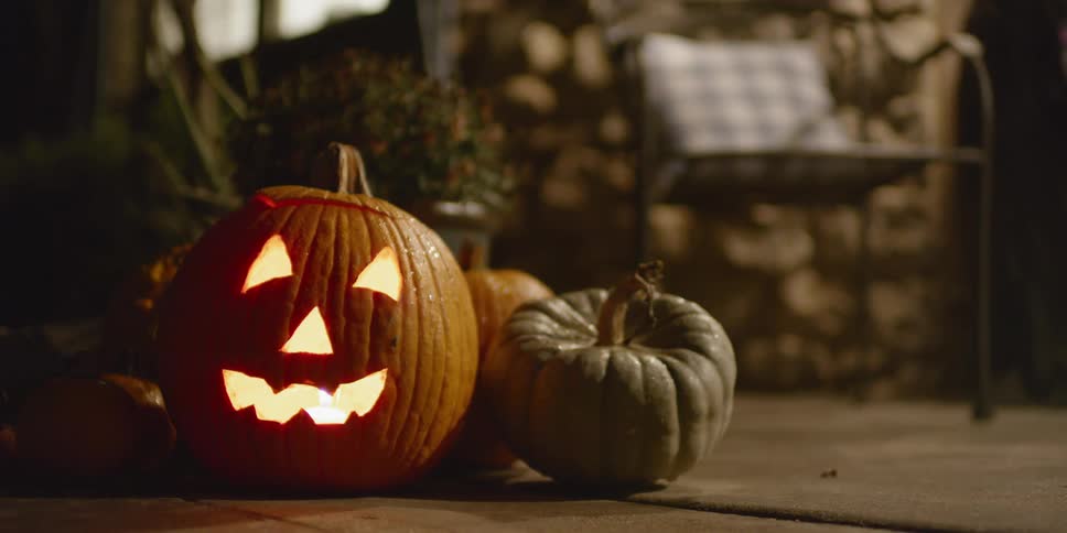 A jack o lantern is illuminated on a house porch