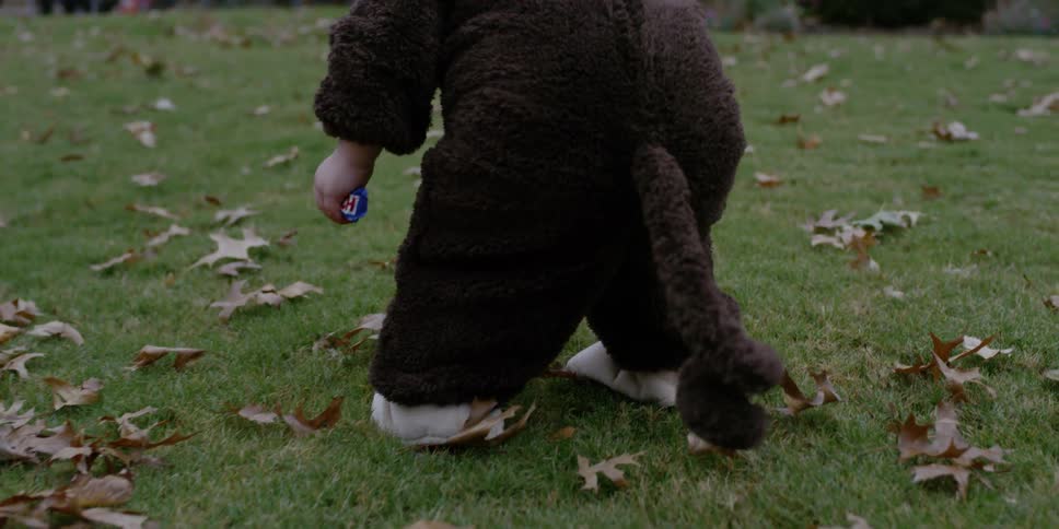 Children wearing halloween costumes run in a leafy yard