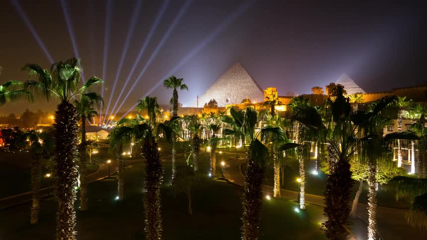 Laser lights and palm trees near a pyramid
