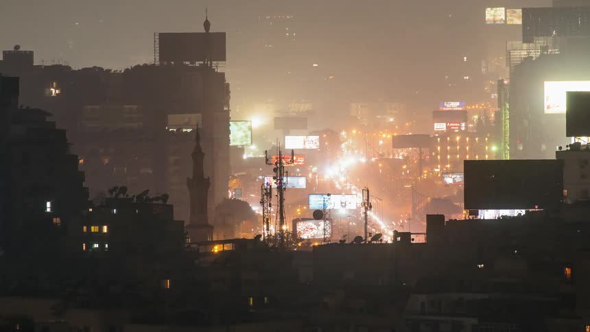 Traffic is flowing through a city on a foggy night