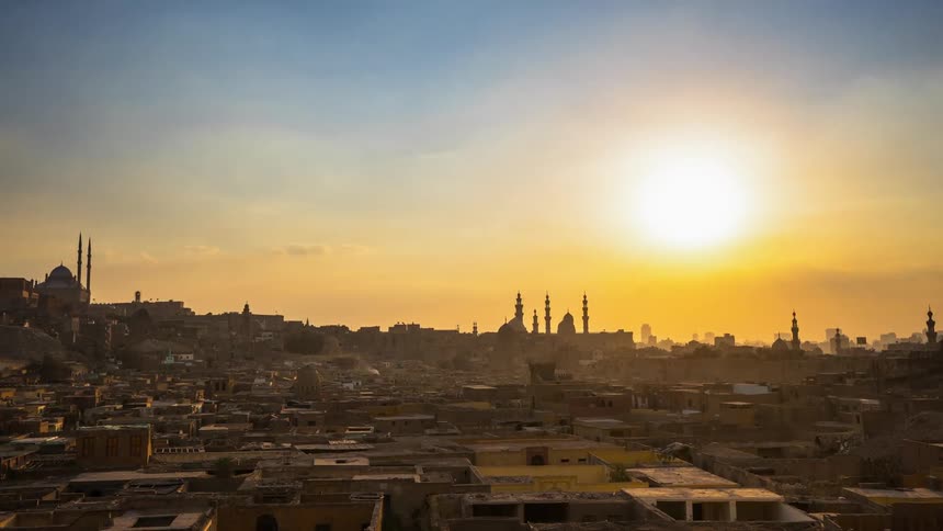 Clouds are moving across a city with minarets as the sun sets
