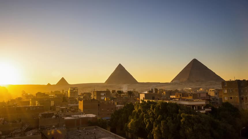 The sun sets over pyramids and stone buildings