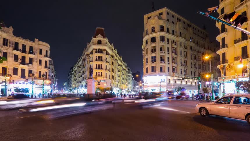 Pedestrians and vehicles commute through a city at night