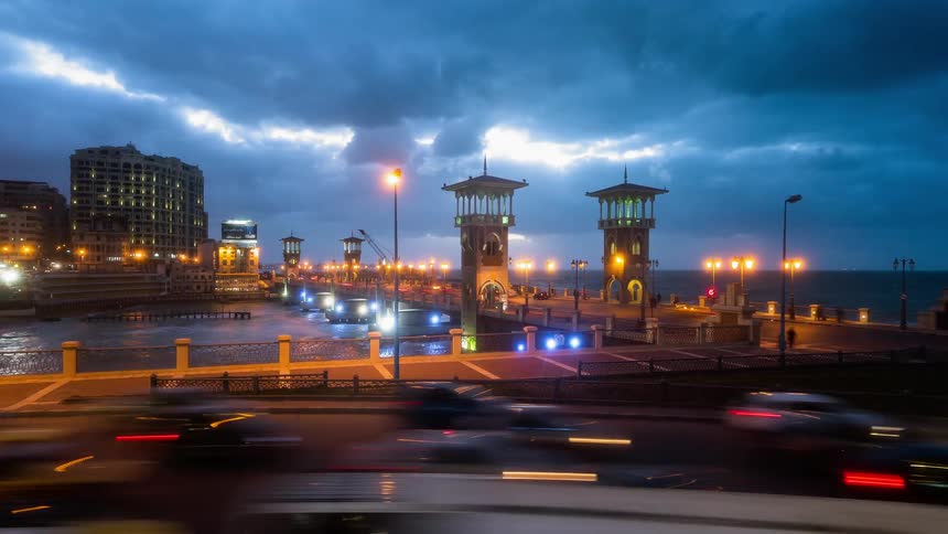 Cars drive on a city waterfront at dusk