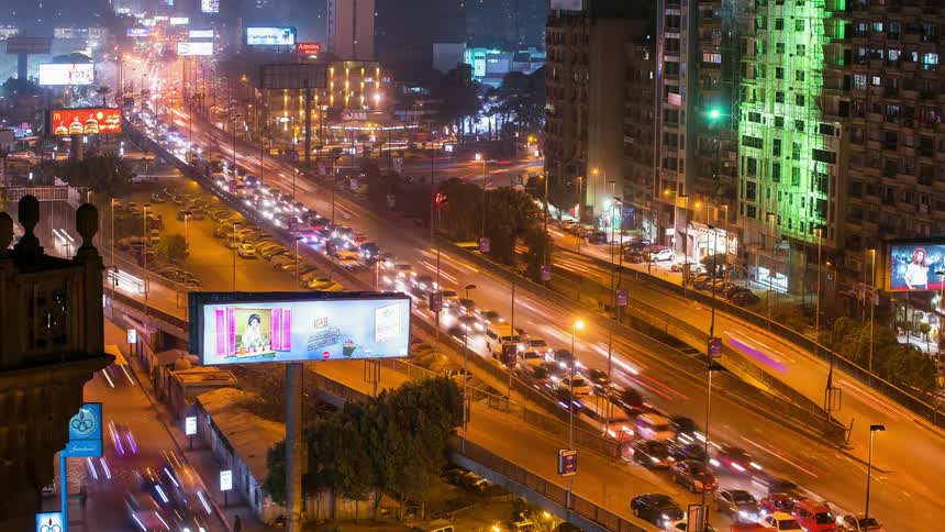 Cars driving through a lit up city at night
