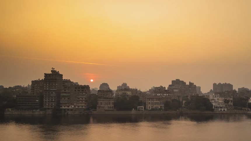 A river flows in front of buildings at sunset