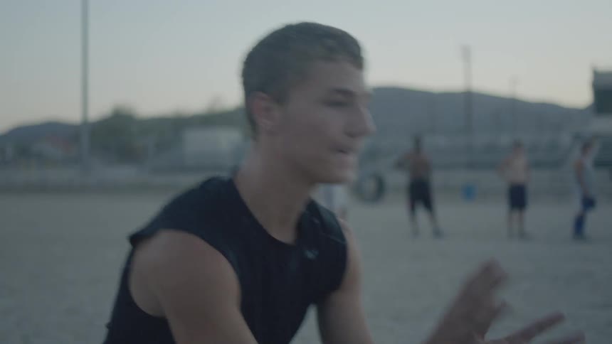 Man rubs his hands in sand then catches and throws a football