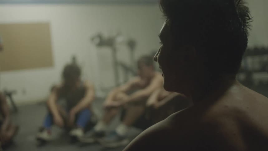 Shirtless men lying on a floor and sitting up at the same time