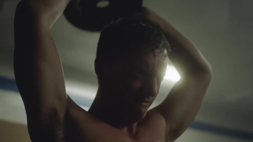 A white male teenager works out hard with weights in a gym