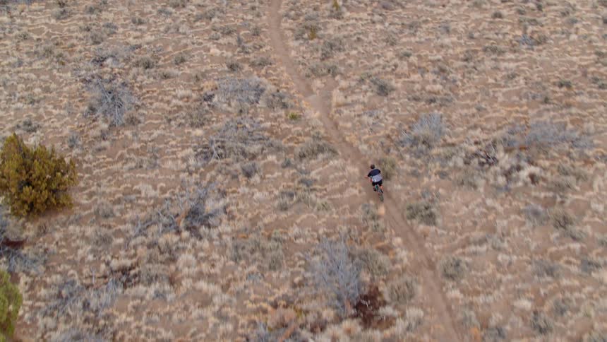 A bicyclist rides on a rural dirt path