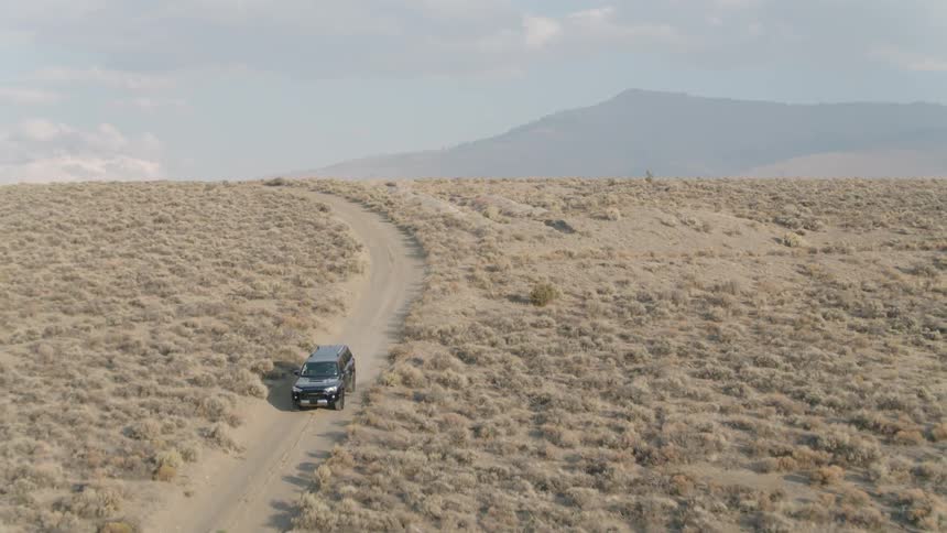 A vehicle drives on a rural desert road