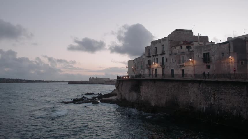 A car drives around the building by the shore