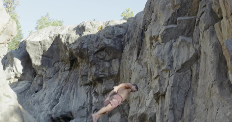 A man does a backflip off a cliff and lands in water