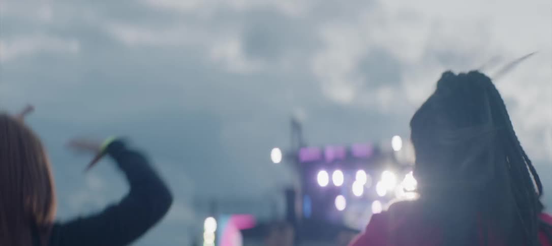 Two people dance and cheer outside at a concert