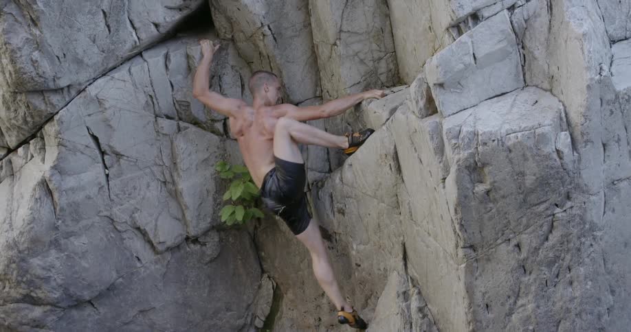 A man climbs up rocks from the water