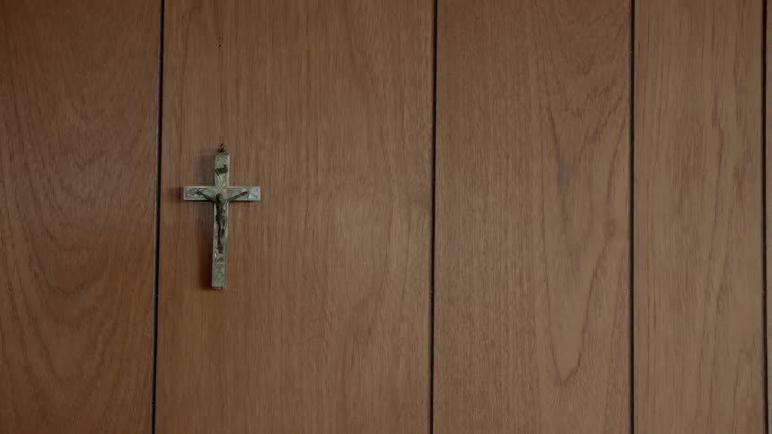 A cross hangs on a wood panel wall