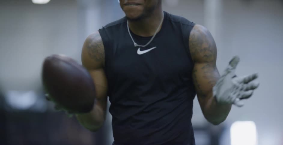 An athlete smiles while holding a football