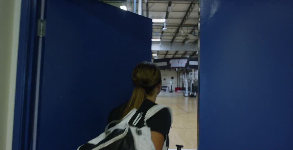 An athlete carries a duffel bag into a gymnasium