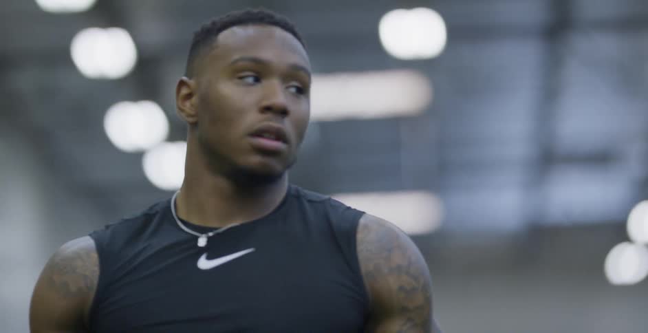 An athlete tosses a football from behind his back and catches it