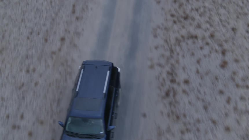 A truck drives on a dirt road
