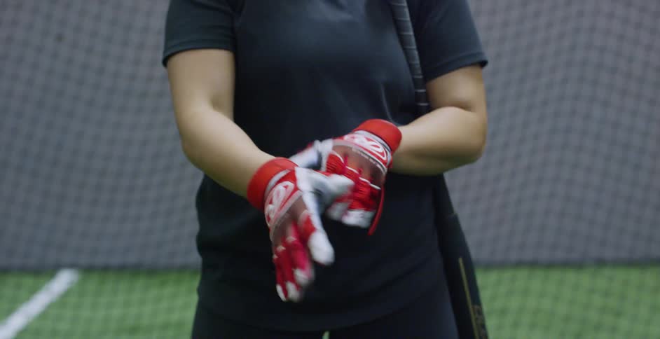 Woman puts on gloves while standing near a net